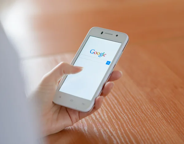 ЗАПОРИЖЬЯ, УКРАИНА - 23 ЯНВАРЯ 2015: Молодая женщина использует Google Web Search на своем смартфоне . — стоковое фото