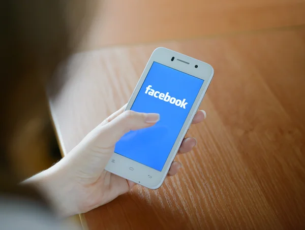 ZAPORIZHZHYA, UKRAINE - JANUARY 23, 2015: Young Woman Using Facebook Social Network Application on her Smart Phone. — Stock Photo, Image