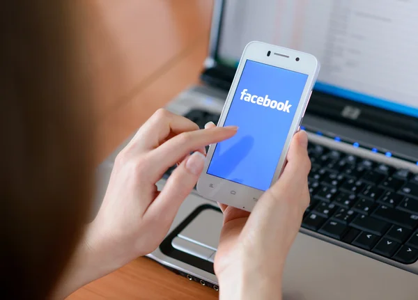 ZAPORIZHZHYA, UKRAINE - JANUARY 23, 2015: Young Woman Using Facebook Social Network Application on her Smart Phone. — Stock Photo, Image