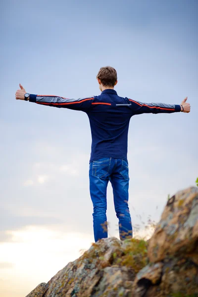Young Man Standing on Mountain Peak with Arms Raised. Active Lifestyle Concept. — Stock fotografie