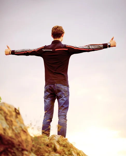Молодой человек стоит на вершине горы с поднятыми руками. Концепция активного образа жизни . — стоковое фото