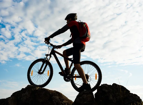 Silhouette eines Radfahrers mit Fahrrad auf dem Felsen bei Sonnenuntergang. Extremsport. — Stockfoto