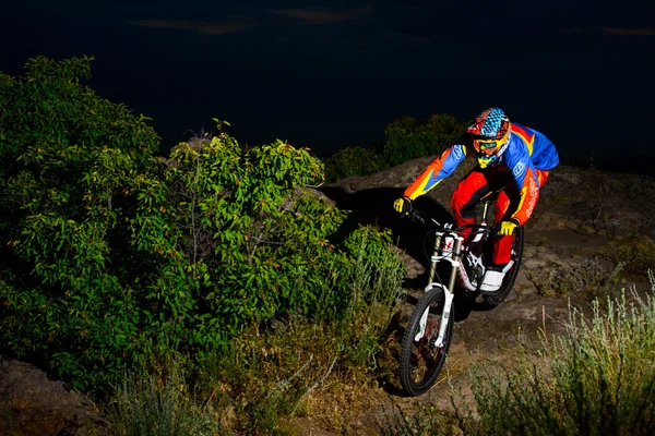 Fully Equipped Professional Downhill Cyclist Riding the Bike on the Night Rocky Trail — Stockfoto