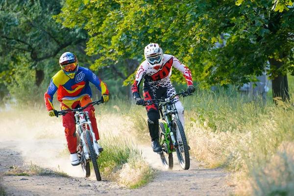 Dos ciclistas profesionales en descenso totalmente equipados que montan bicicletas en el sendero de verano — Foto de Stock