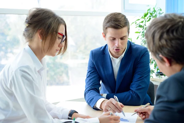 Gli uomini d'affari che analizzano i risultati finanziari sui grafici intorno alla tabella nell'ufficio moderno. Concetto di lavoro di squadra — Foto Stock