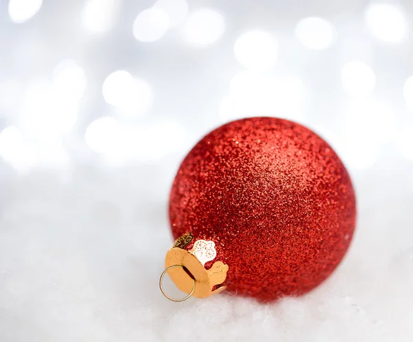 Decoración de Navidad con bola roja en la nieve en el fondo borroso con luces navideñas. Tarjeta de felicitación —  Fotos de Stock