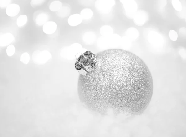 Decorazione natalizia con palla bianca nella neve sullo sfondo sfocato con luci. Biglietto di auguri — Foto Stock