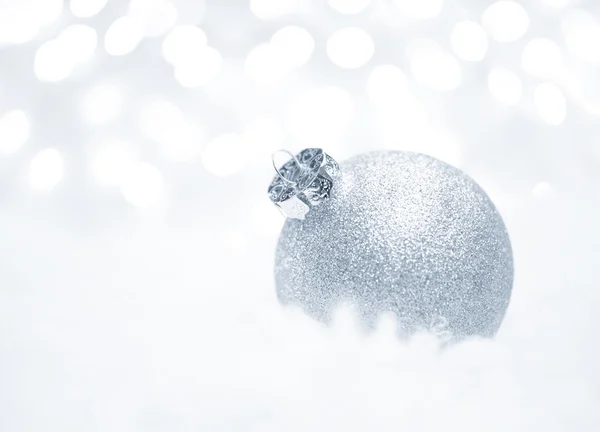 Decoración de Navidad con bola blanca en la nieve sobre el fondo borroso con luces. Tarjeta de felicitación — Foto de Stock