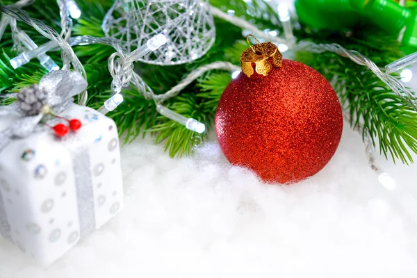 Decoração de Natal com bola vermelha, ramo de abeto verde e luzes brancas na neve. Cartão de saudação — Fotografia de Stock