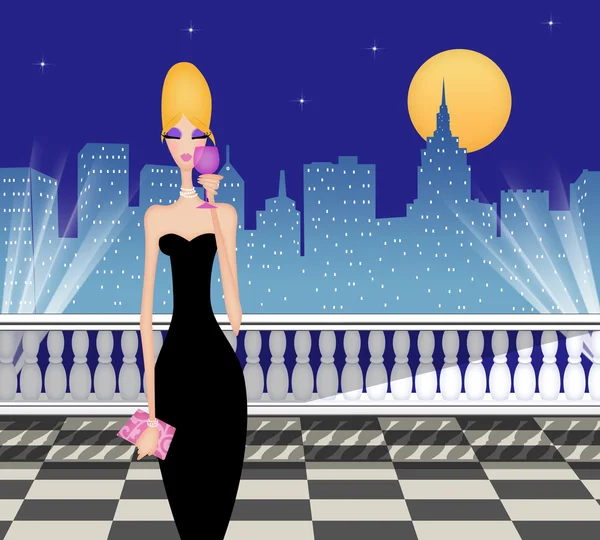 Mulher chique com vinho em um terraço iluminado pela lua na cidade Imagens Royalty-Free