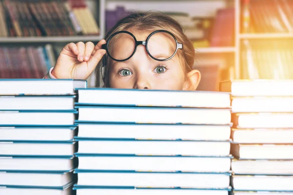 Förskolebarn liten flicka läser en bok i biblioteket - Pupil älskar föreläsning, förbereda sig för skolan. — Stockfoto