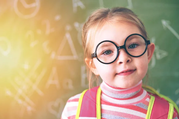 The first day at school. A little school girl stands at the chalk board.