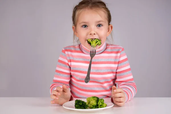 Criança se diverte comendo brócolis — Fotografia de Stock