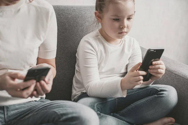 Mom and daughter are addicted to a smartphone. Harm of electronic devices for children.