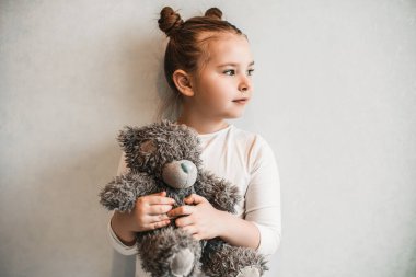 Üzgün küçük kız ayıyla ayakta duruyor