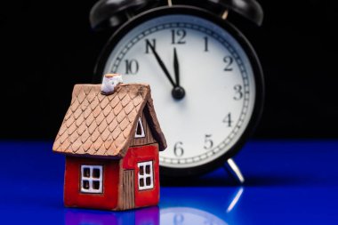 Çalar saati, gayrimenkulü, konut maliyeti veya yeni bir ev konsepti olan mukavva ev modeli.