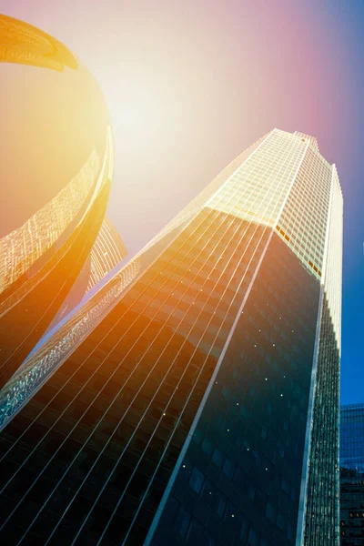 Skyscraper glass facades on a bright sunny day with sunbeams in the blue sky. Modern buildings in Moscow business district La Defense. Bottom up view — Stock Photo, Image