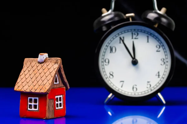 Model of cardboard house with alarm clock, real estate, cost of housing or buying a new home concept. — Stock Photo, Image