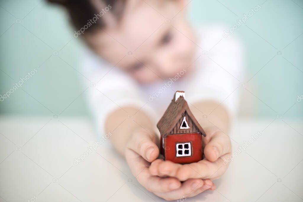 Small child with a red toy house. Selected focus.