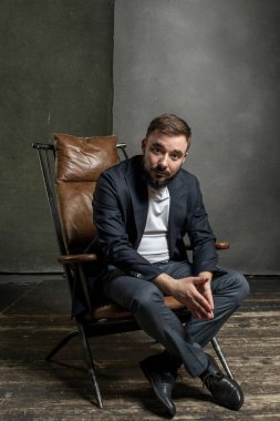 Genç, vahşi bir adam sandalyede oturuyor.