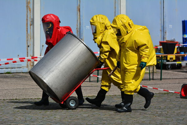 Worker in protective uniform,mask,gloves and boots  transport barrels of chemicals