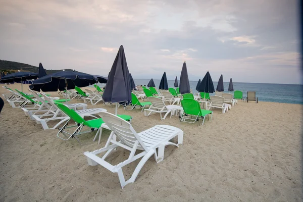 Bir kum plajındaki thatched şemsiye altında boş sandalyeler — Stok fotoğraf