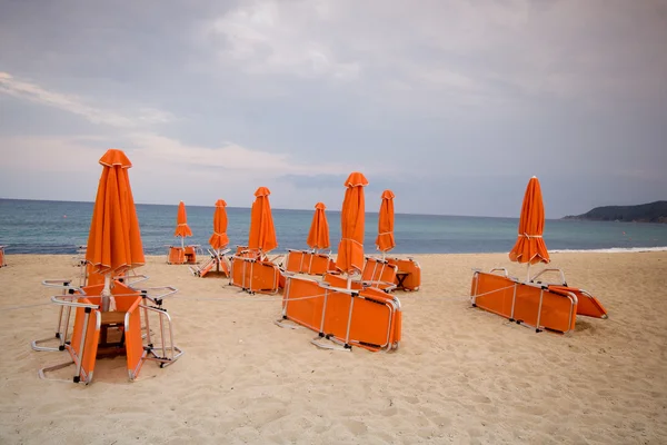 Sedie vuote sotto ombrelloni di paglia su una spiaggia di sabbia — Foto Stock