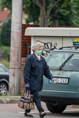 PECS - 27 Mayıs: 27 Mayıs 2020 tarihinde yaşlı kadın Pecs, Macaristan 'da alışverişe gider. Coronavirus salgını sırasında herkes maske takmak zorundadır.