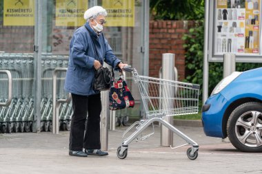 PECS - 27 Mayıs: 27 Mayıs 2020 tarihinde yaşlı kadın Pecs, Macaristan 'da alışverişe gider. Coronavirus salgını sırasında herkes maske takmak zorundadır.