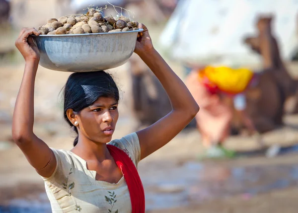 Young Indian woman carrying a basin on her head of camel dung. — Stock Photo, Image