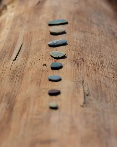 Small flat rocks on the wooden beam — Stock Photo, Image