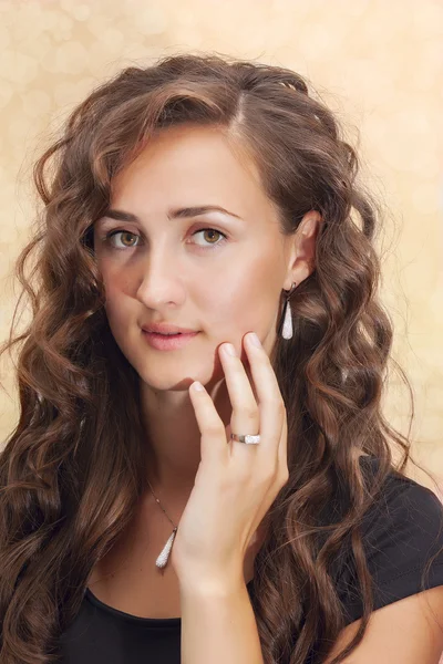 Femme souriante en robe noire portant bague en diamant sur fond de lumières dorées — Photo