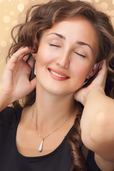 Sorrindo mulher em vestido preto usando anel de diamante sobre luzes douradas fundo — Fotografia de Stock