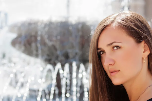 Portrait of a beautiful girl on a background of a fountain — Stock Photo, Image