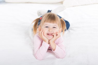 sevimli gülümseyen küçük kız beyaz yatakta