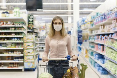 Koruyucu maskeli genç bir kadın alışveriş yapıyor. Salgın bir alışveriş merkezinde alışveriş yapıyor.