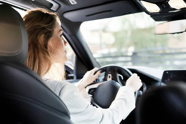 A businesswoman is driving a luxury car