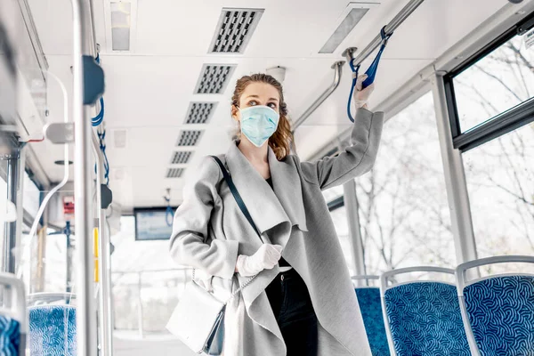 Toplu taşıma araçlarında maske ve eldiven takan genç bir kadın..