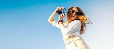 Genç bir kadın yazın şehri gezerken mutlu ve gülümsüyor. Kadın kamerayı tutuyor..