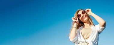 Genç bir kadın yazın şehri gezerken mutlu ve gülümsüyor. Kadın kamerayı tutuyor..