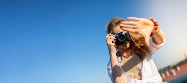 Genç bir kadın yazın şehri gezerken mutlu ve gülümsüyor. Kadın kamerayı tutuyor..