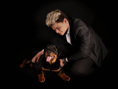 safkan Rottweiler ve genç siyah arkaplan önünde