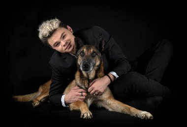 Siyah arka planda Belçikalı çoban ve genç adam.