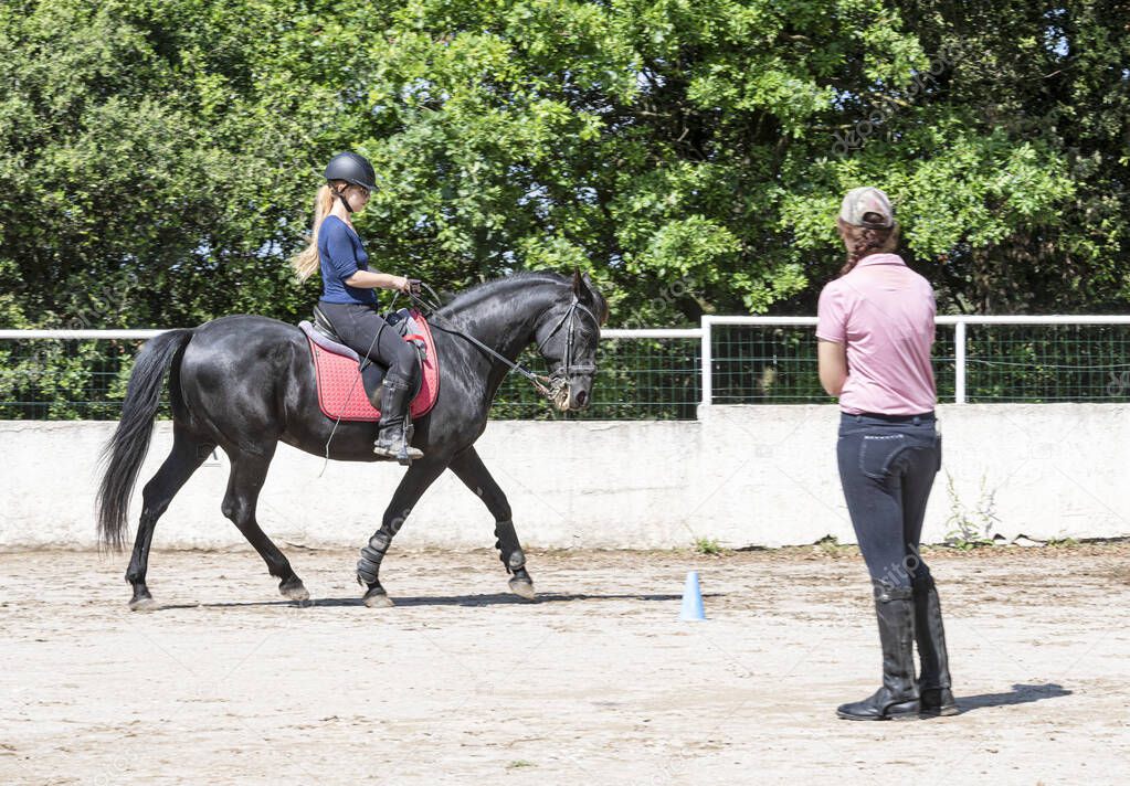 riding girl and teacher are training her black horse
