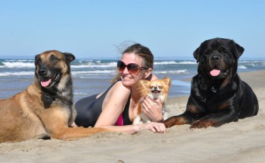 Kadınlar ve köpekler yazın dalgalarda oynuyorlar.