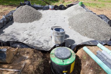 Installing a sand and gravel filter bed for a household septic tank for the disposal and purification of sewage, effluent and waste water. Low angle view from the pump along the length of the filter bed showing the  two filters, liner, sand,  gravel,