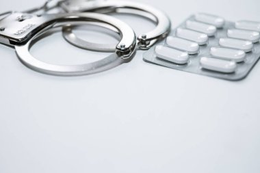 Kelepçe, hap ve uyuşturucu beyaz masada..