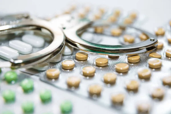 Esposas y pastillas y medicamentos en la mesa blanca. — Foto de Stock