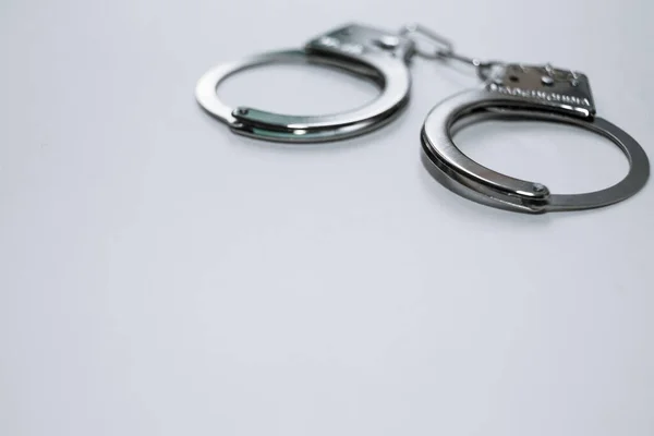 Handcuffs on a white background in the upper left corner of the frame. — Stock Photo, Image