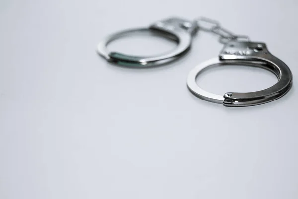 Handcuffs on a white background in the upper left corner of the frame. — Stock Photo, Image